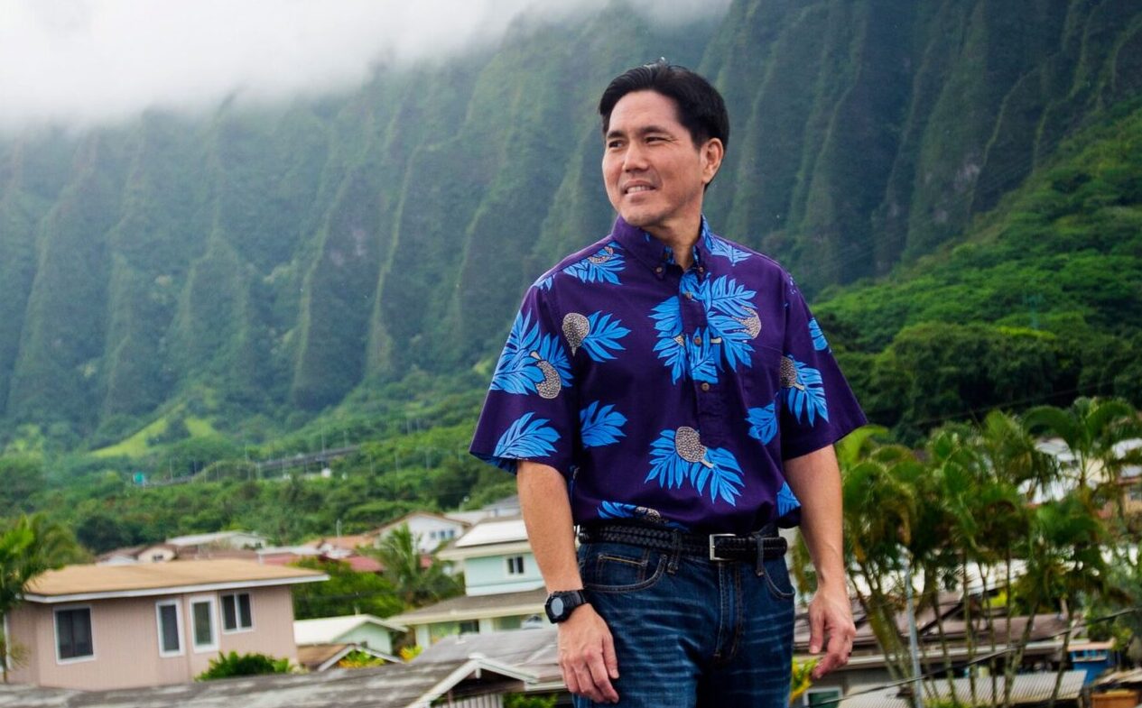 Isaac in blue shirt standing near solar panels